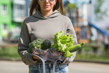 A modern stylish woman with a shopping bag, buying green vegetables against the background of the...