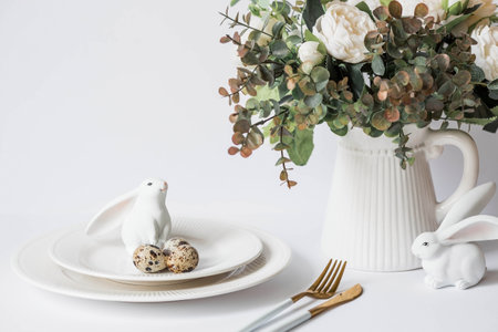 Banner. The concept of a bright Easter holiday. A bouquet of flowers with feathers, white rabbits and Easter eggs in a plate on a white isolated background. Beautiful Easter card.の写真素材