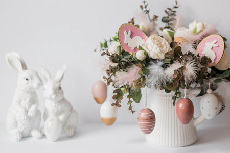 Banner. The concept of a bright Easter holiday. A bouquet of flowers with feathers and white rabbits on a white isolated background. Beautiful Easter card.の写真素材