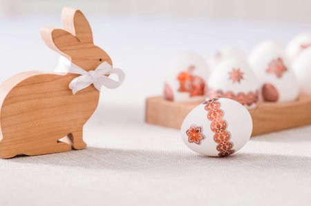Wooden Easter bunny with a bow and Easter eggs on a linen tablecloth on the table. The concept of the Bright Easter holiday.の写真素材