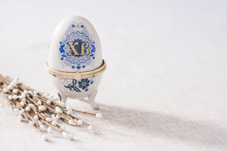 A large egg box with the inscription XB and a willow on a linen tablecloth on the table. The concept...