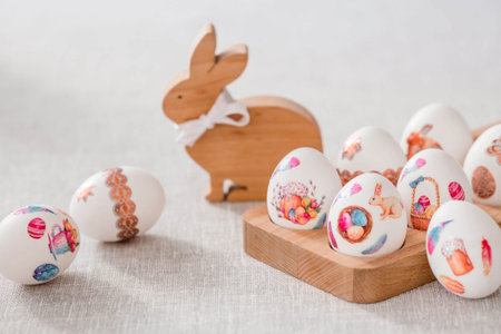 Wooden Easter bunny with a bow and Easter eggs on a linen tablecloth on the table. The concept of...