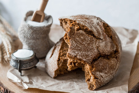 Fresh delicious bread close-up and salt. Freshly baked sourdough bread with a golden crust on a wooden board. The context of a bakery with delicious bread. confectionery products.の写真素材