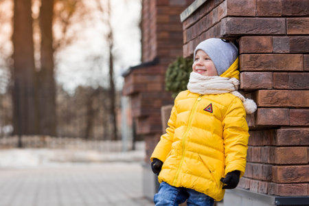Portrait of a small child 4 years old in yellow rubber boots and a jacket. The kid walks in the park in the spring. Photo of spring and autumn holidays.の写真素材