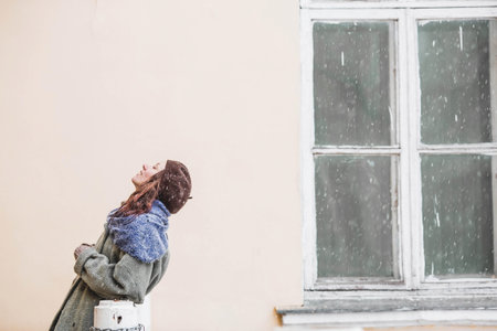 Portrait of a cute young woman in a beret in early spring outdoors. A girl with loose hair and a long coat on the background of an old manor.の写真素材