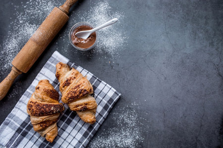 Delicious freshly baked croissants with chocolate on a dark background. french breakfast. Delicious pastries close-up. The context of a bakery with delicious bread. confectionery products.の写真素材