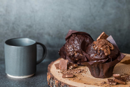 Delicious freshly baked chocolate muffins on a dark background. Delicious cupcake close-up. The context of a bakery with pastries. confectionery products.の写真素材