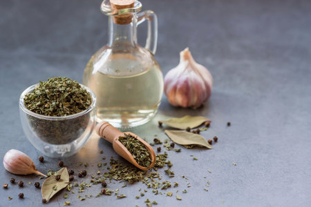 Fragrant spices. Dried parsley, garlic, bay leaf, black pepper and a bottle of oil on a gray background. free space.の写真素材