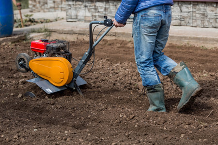 Banner. Man Farmer plows the land with a cultivator. Agricultural machinery: cultivator for tillage in the garden,motor cultivator.の写真素材