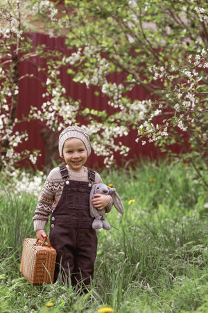 A little boy of 4 years old outdoors with a suitcase and a stuffed rabbit goes on a journey. A...