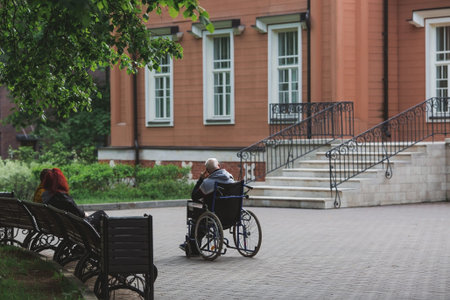An elderly man in a wheelchair walks in the park outdoors. Disability. Health problems. Medicine,...