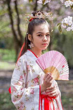 Portrait. Beautiful girl in Japanese kimano in a Japanese garden on the background of cherry blossoms. Cherry blossoms in the garden in the Biryulevsky arboretum. Russia, Tsaritsyno, 2023.のeditorial素材