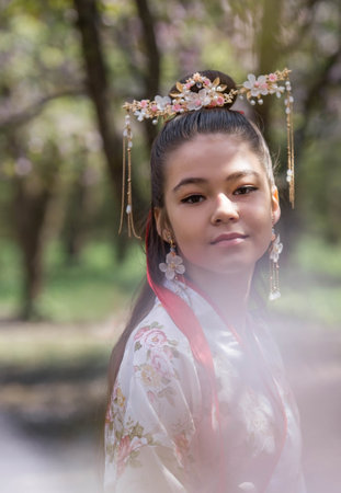 Portrait. Beautiful girl in Japanese kimano in a Japanese garden on the background of cherry blossoms. Cherry blossoms in the garden in the Biryulevsky arboretum. Russia, Tsaritsyno, 2023.のeditorial素材