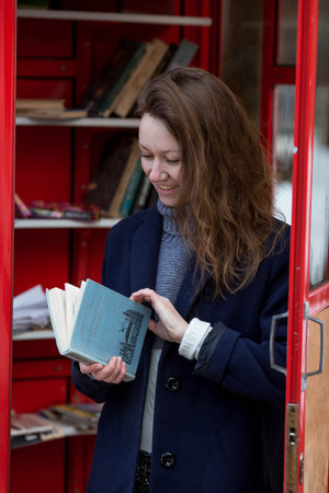 Portrait of a young woman over 30 years old with a book in her hands, a girl took a book from a street library. Modern lifestyle, reading books and education.の写真素材