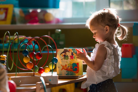 A cute little girl of 3 years old is playing educational toys in a kindergarten group. Portrait of a child.の写真素材