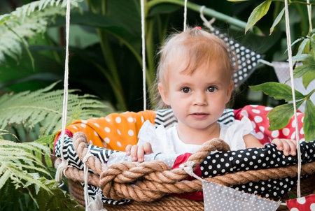 Cute little girl in a balloon basket. The child is playing in nature. The concept of travel and children's outdoor games.の写真素材