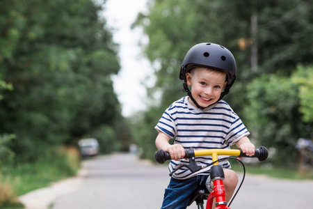 A cheerful little boy rides a running bike in a helmet outdoors. A happy child is engaged in an active sport. protection. Life insurance and child safety.の写真素材