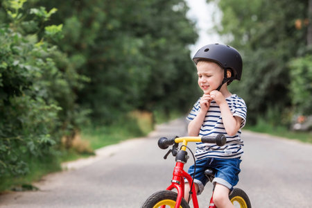 A cheerful little boy rides a running bike in a helmet outdoors. A happy child is engaged in an active sport. protection. Life insurance and child safety.の写真素材