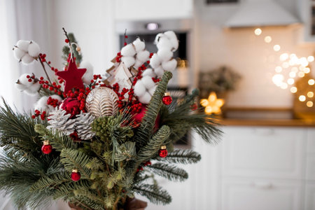 A spruce bouquet with red berries, toys, cotton on a white kitchen table. Christmas decorations in the interior. The concept of preparation for the New Year's holiday 2024.の写真素材