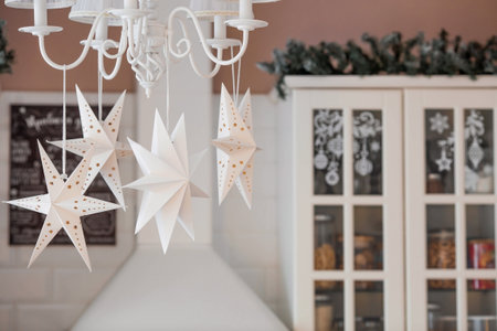 White Scandinavian paper stars in the Christmas decoration of the kitchen interior. The concept of preparation for the New Year holidays in 2024.の写真素材