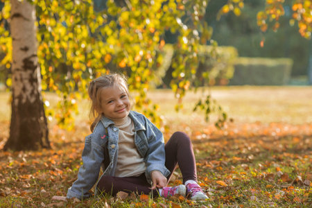 Portrait of a little girl 4 years old outdoors. A happy child in the autumn park. Happy childhood and fatherhood.の写真素材