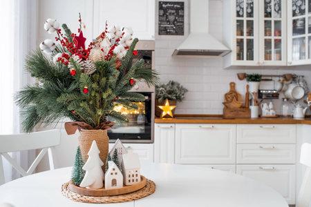 A spruce bouquet with red berries, toys, cotton on a white kitchen table. Christmas decorations in the interior. The concept of preparation for the New Year's holiday 2024.の写真素材
