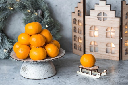 Christmas New Year background with tangerines, toys, wooden houses and a fir wreath with a garland. Festive treats and decorations. Russian traditions.の写真素材