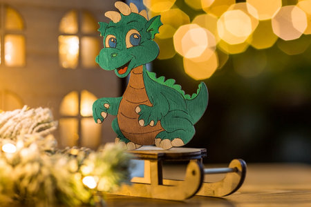 Zodiac sign. A New Year's toy in the form of a green wooden dragon on the background of a garland and a beautiful bokeh. Glowing Christmas holiday background. Chinese horoscope for 2024.の写真素材