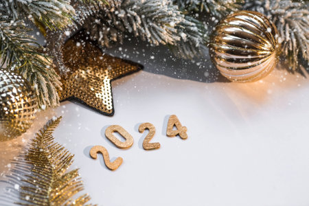 Banner. Happy New Year and Merry Christmas. Golden numbers 2024, snow, fir branches and Christmas tree toys on a white background. The flyer. Invitation.の写真素材
