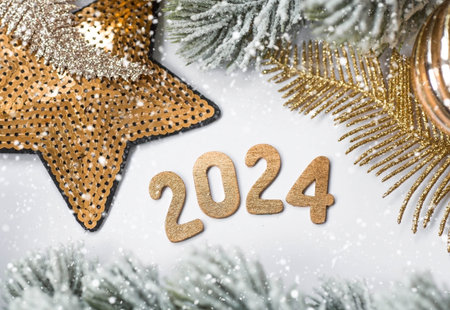 Banner. Happy New Year and Merry Christmas. Golden numbers 2024, snow, fir branches and Christmas tree toys on a white background. The flyer. Invitation.の写真素材