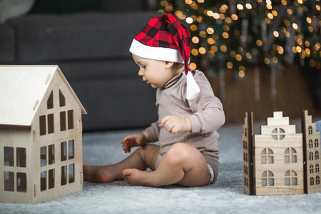 Family. A beautiful little blond boy of 1 year old is sitting on the background of a Christmas tree. The concept of celebrating Christmas and New Year 2024.の写真素材