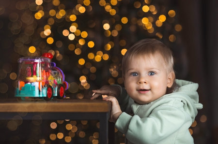 Family. A beautiful little blond boy of 1 year old is sitting on the background of a Christmas tree....