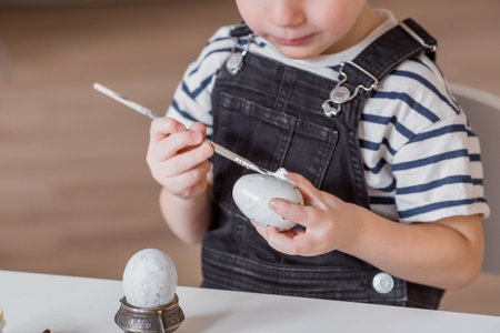 A little boy paints eggs on Maundy Thursday for the holiday. We are preparing the family for a...