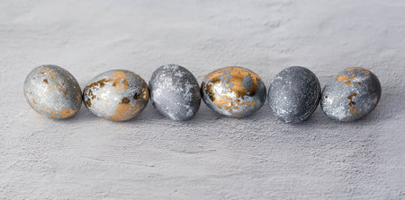 Stylish gray Easter eggs made of marble and concrete with a golden potala on a gray background. Coloring eggs with natural dye karkade tea. Environmental friendliness. Naturalness. The concept of a happy Easter.の写真素材