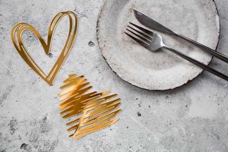 The banner. Table setting. Stylish ceramic plate and gold, red hearts on a concrete background. The concept of celebrating Valentine's Day for cafes and restaurants.の写真素材