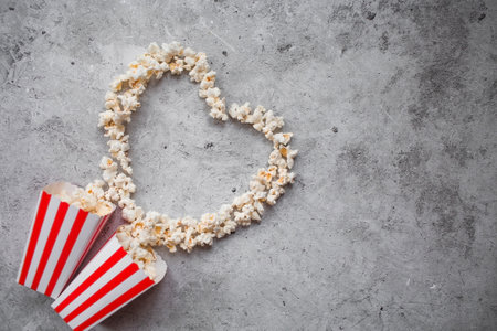 A banner for the film industry. A romantic movie date. A popcorn heart and retro striped cups on a stylish concrete-gray background. The film will premiere on Valentine's Day.の写真素材