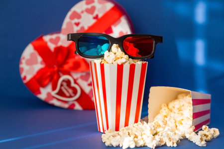 A banner for the film industry. A romantic movie date. A movie camera, 3D glasses, popcorn and red hearts on a blue background. The film will premiere on Valentine's Day.の写真素材