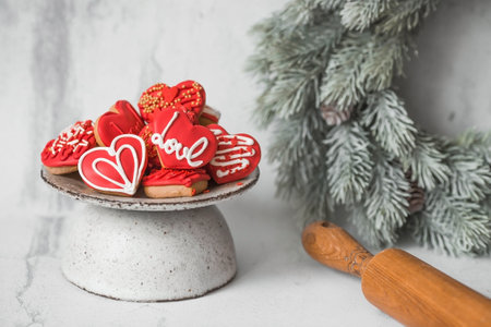 Homemade ginger cookies in the shape of a heart in red icing sugar. Delicious ginger cookies heart on a light concrete background. Freshly baked gingerbread cookies for Valentine's Day.の写真素材