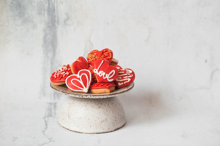 Homemade ginger cookies in the shape of a heart in red icing sugar. Delicious ginger cookies heart on a light concrete background. Freshly baked gingerbread cookies for Valentine's Day.の写真素材