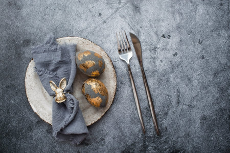 The banner. Table setting. A fashionable concrete plate with a rabbit on a napkin, Easter eggs with...