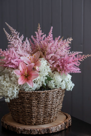 A beautiful, delicate bouquet of pink lilies, white hydrangea and pink astilbe in a wicker basket in the interior. Close-up. Decor.の写真素材
