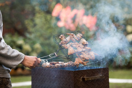 Barbecue at the cottage. May holidays. Barbecue in nature. The process of cooking meat on the grill,...