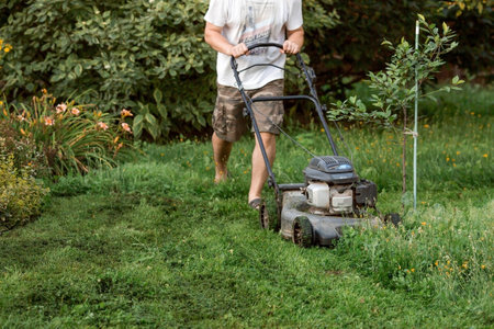 Banner. A human lawn mower cuts the grass in the backyard. Agricultural machinery for the care of the garden.の写真素材