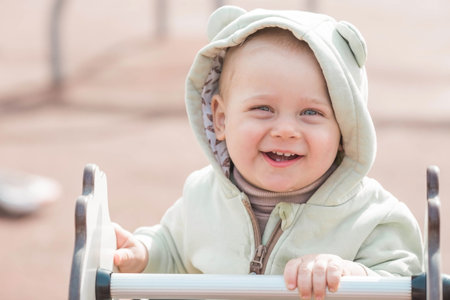 A beautiful, cheerful little boy of two years old walks on the playground in the spring. The concept of parenthood, childhood and family.の写真素材