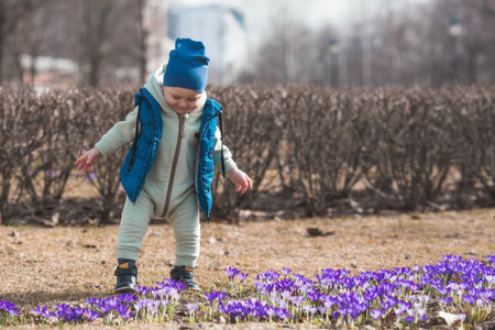 A handsome, cheerful little boy of two years old walks with his mother on the street in the spring....