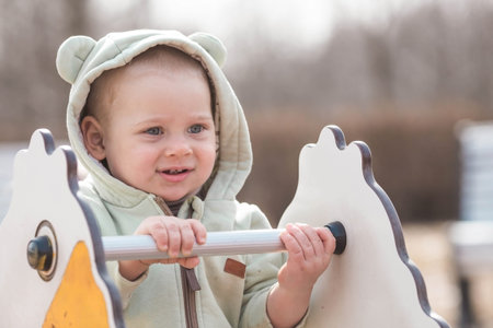 A beautiful, cheerful little boy of two years old walks on the playground in the spring. The concept...