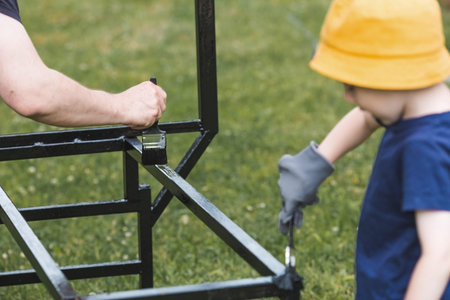 Father and son work with a brush and apply black paint to the rust. People paint metal structures....