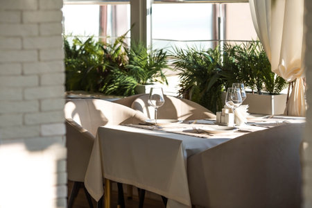 Stylish table setting. Glass glasses, plates, cutlery on the table. Wedding service, reception at the dining table. A birthday, a baptism, a festive event.の写真素材