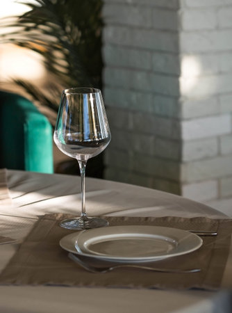 Stylish table setting. Glass glasses, plates, cutlery on the table. Wedding service, reception at...