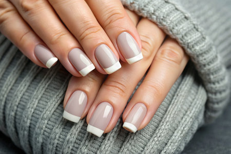 A magnificent French manicure. Transparent nail polish. Close-up photo of hands. Women's hands on a simple background.の素材